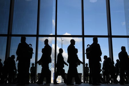 Silhouettes of people against a glass building facade.