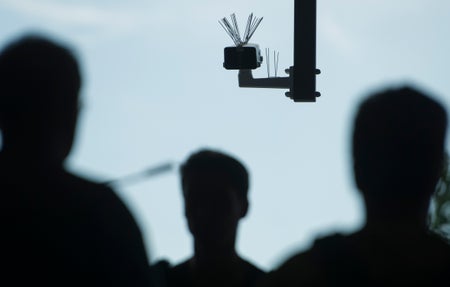 Shadows of 3 people walking under a surveillance camera