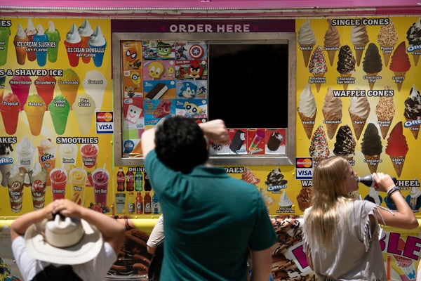 Three people waiting in front of ice cream truck window.