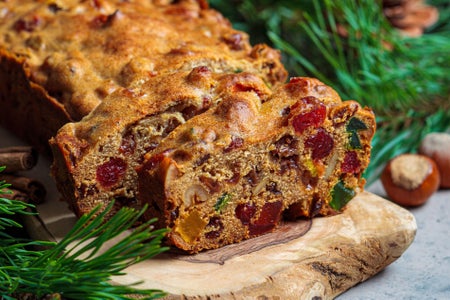 Traditional Christmas fruit cake on a wooden board in a festive decoration, dark background