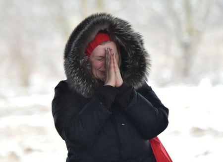 A woman reacts as her relatives cross a destroyed bridge leaving the Ukrainian city of Irpin on March 8.