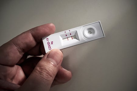 Close-up of adult hand holding a positive result Covid19 or SARS CoV-2 test kit