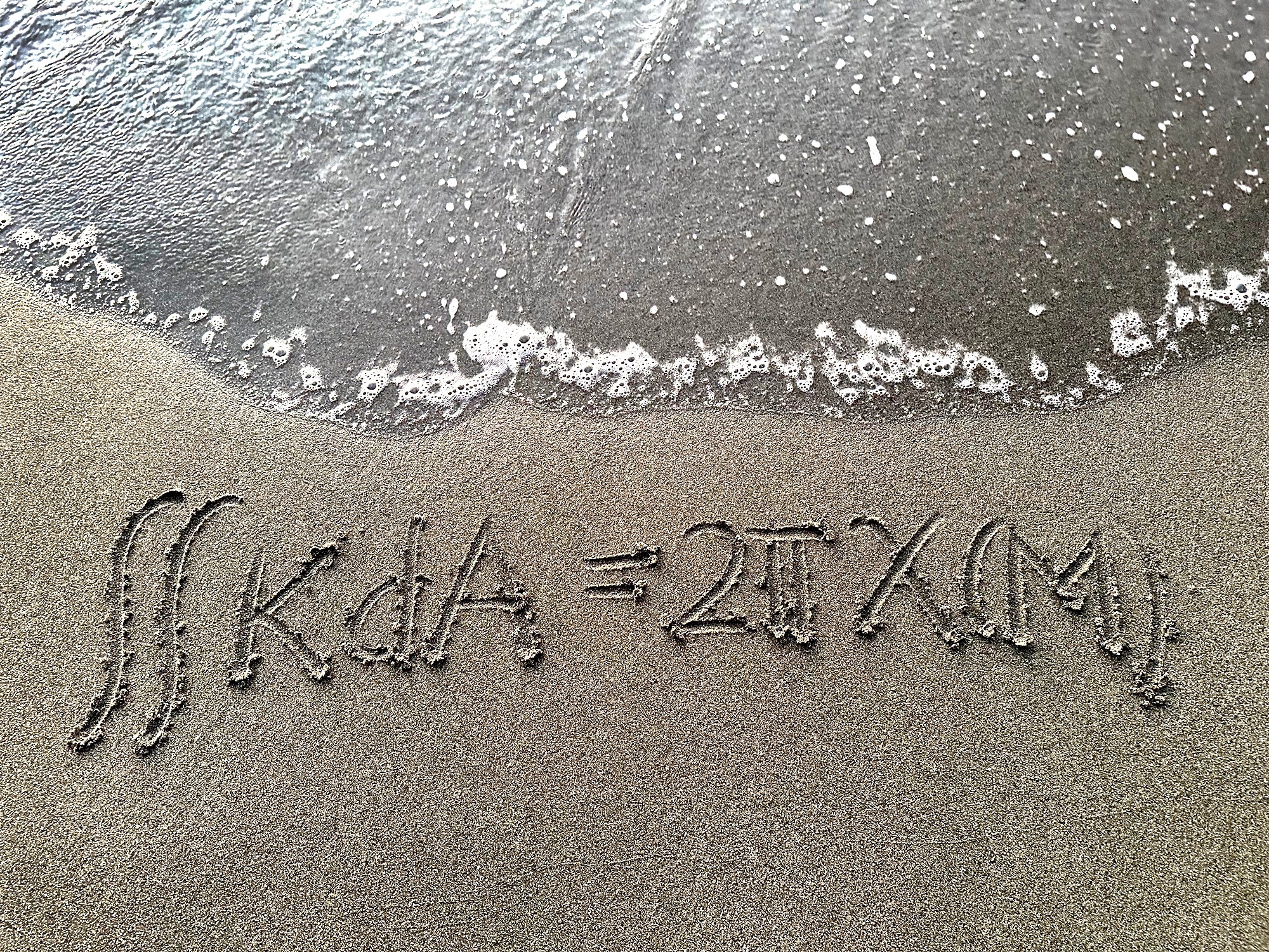 Math equation written in sand.