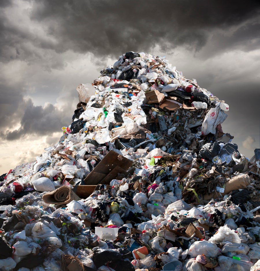 Trash mountain at dump with stormy clouds.