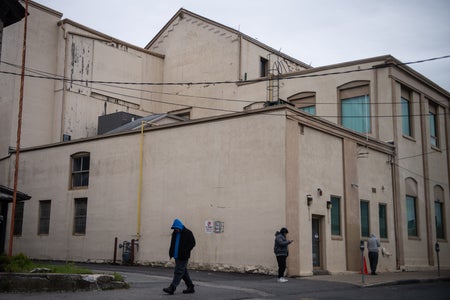 Three unidentifiable people walking outside a clinic