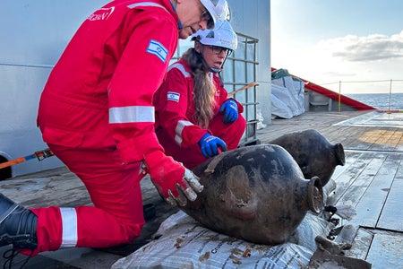 IAA archaeologist Jacob Sharvit, left, and Energean environmental lead Karnit Bahartan, examine two Canaanite storage jars after their retrieval from the seafloor of the Mediterranean on May 30, 2024.